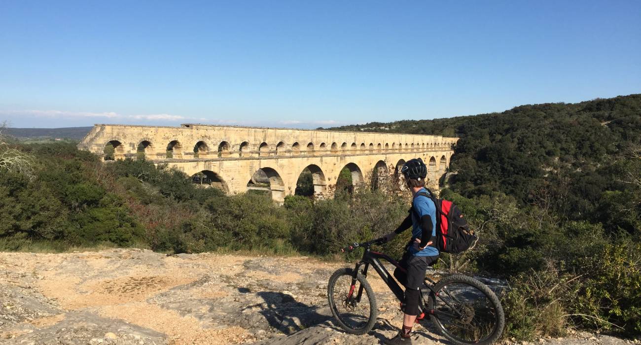 Homme à vélo devant le pont du Gard